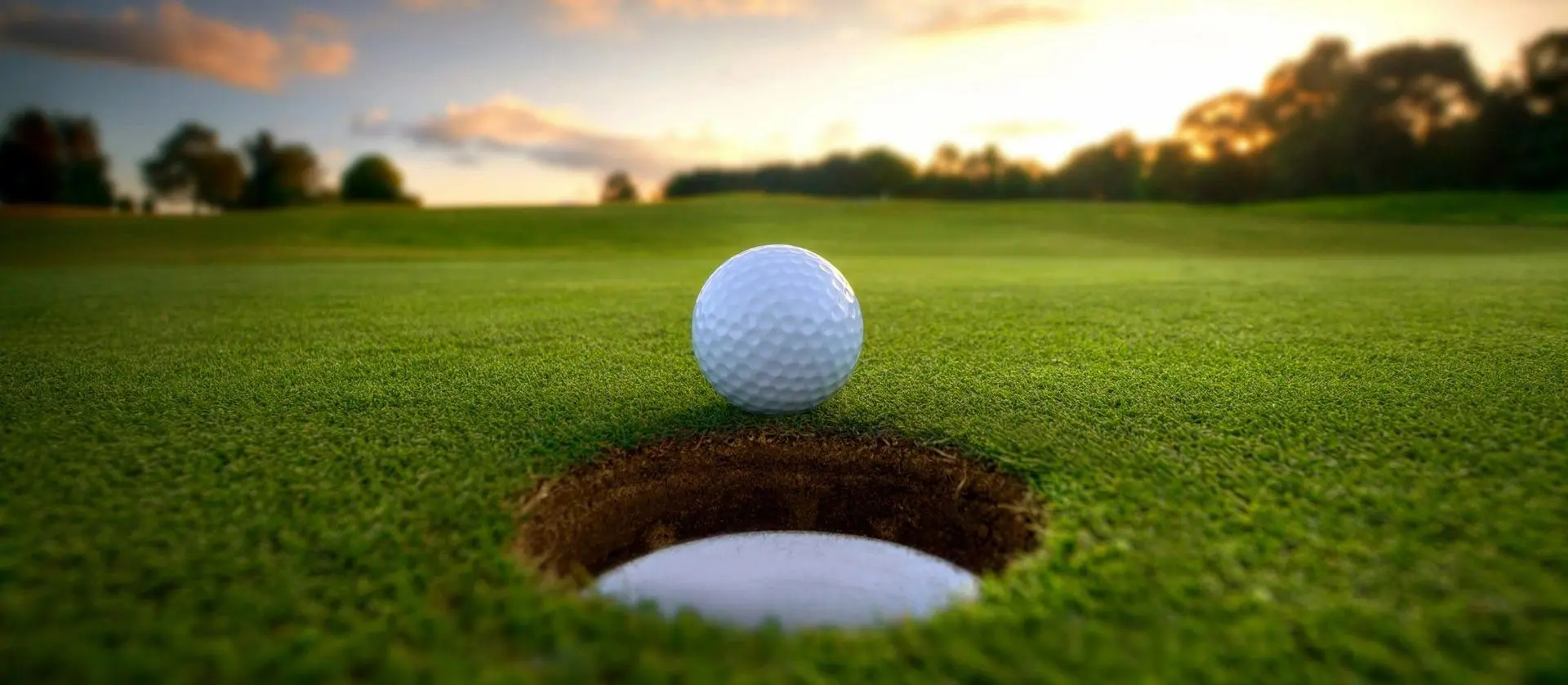 A golf ball is in the hole and ready to hit.